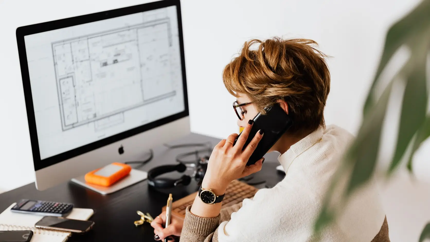 Professional taking notes during a phone call at a desk